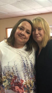 two women posing for a photo in a room