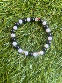 a black and white beaded bracelet on grass