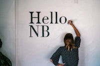 a woman writing hello nb on a wall