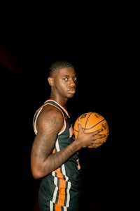 a basketball player holding a ball in front of a dark background