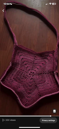 a purple crocheted bag on a wooden floor
