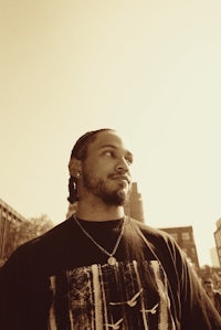 a man with dreadlocks standing in front of a building