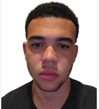 a young man in a black shirt is looking at the camera