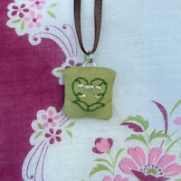 a green heart shaped pendant with a brown cord