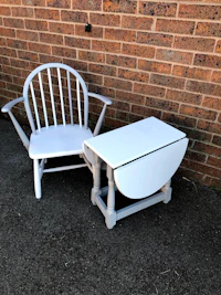 a white rocking chair and table next to a brick wall