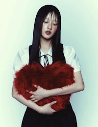 a girl holding a red heart shaped pillow