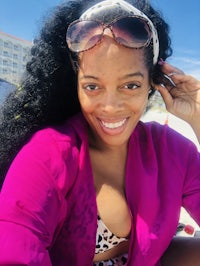 a woman wearing a pink bikini and sunglasses on the beach