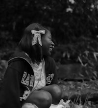 a black and white photo of a girl sitting on the ground