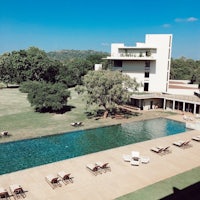 a pool with lounge chairs in front of a building