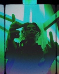 a person is making a peace sign in front of a green screen