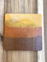 a wooden coaster with a brown, yellow and orange design