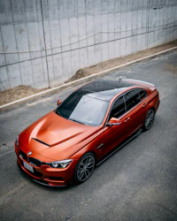 an orange bmw m5 parked in front of a concrete wall