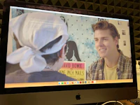 a computer screen showing a man talking to another man
