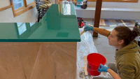 a woman is painting a countertop in a kitchen