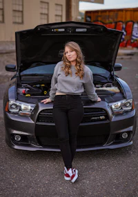 a young woman posing next to her car