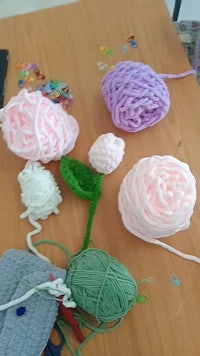 a table with a bunch of yarn and knitting needles