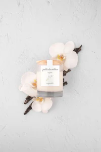 a white candle with vanilla and orchids on a white background