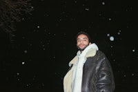 a man in a leather jacket standing in the snow
