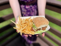 a woman holding a burger and french fries