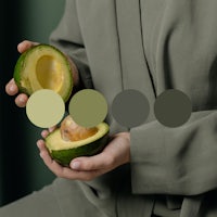 a woman holding an avocado in front of a color palette