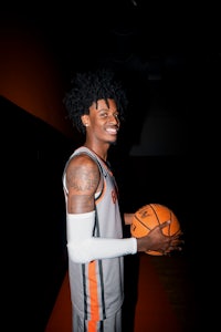 a basketball player holding a ball in an orange and black gym