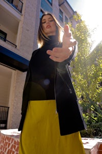 a woman wearing a yellow skirt and black jacket