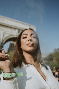 a woman smoking a cigarette in front of the arc de triomphe