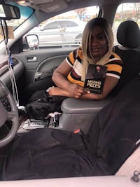 a woman sitting in the back seat of a car holding a book