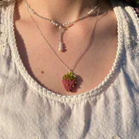 a woman wearing a necklace with a strawberry on it