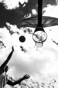 a black and white photo of a basketball player in the air