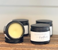 three jars of homemade lip balm sitting on a wooden table