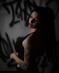 a woman with tattoos posing in front of graffiti