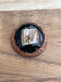 a black and brown stone brooch on a wooden table