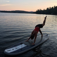 a woman doing a yoga pose on a stand up paddle board