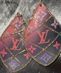 a pair of louis vuitton earrings on a black background
