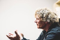 a man with curly hair talking to a group of people