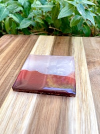 a red and pink glass coaster on a wooden table