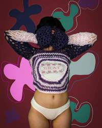 a woman in a crocheted top covering her face