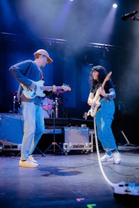 two people playing guitars on stage