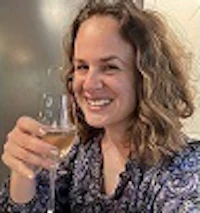 a woman is smiling while holding a glass of wine