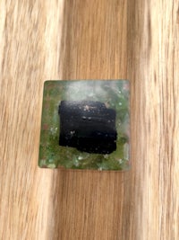 a piece of black and green tourmaline on top of a wooden table