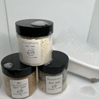three jars of bath salts next to a bathtub