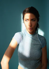 a woman is posing in front of a blue wall