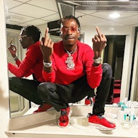 a man in a red shirt is posing in front of a mirror