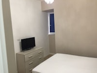 a small bedroom with a bed, dresser and tv