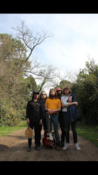 a group of people standing on a dirt road with guitars