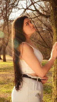 a young woman leaning against a tree