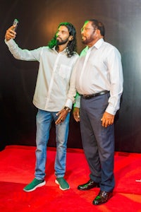 two men standing on a red carpet taking a selfie