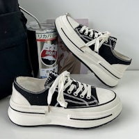 a pair of black and white sneakers next to a bag