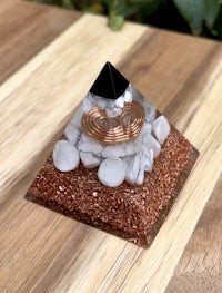 a pyramid with copper and white stones on top of a wooden table